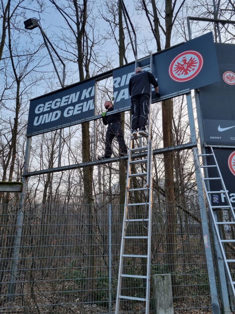 EMS-Team montiert ein Banner an einer Tribüne