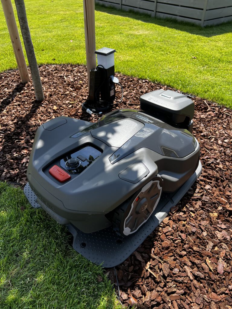 Mähroboter an seiner Ladestation im Garten